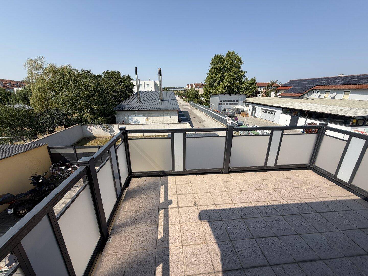 Große Außenterrasse mit moderner Brüstung und Blick auf die Umgebung.
