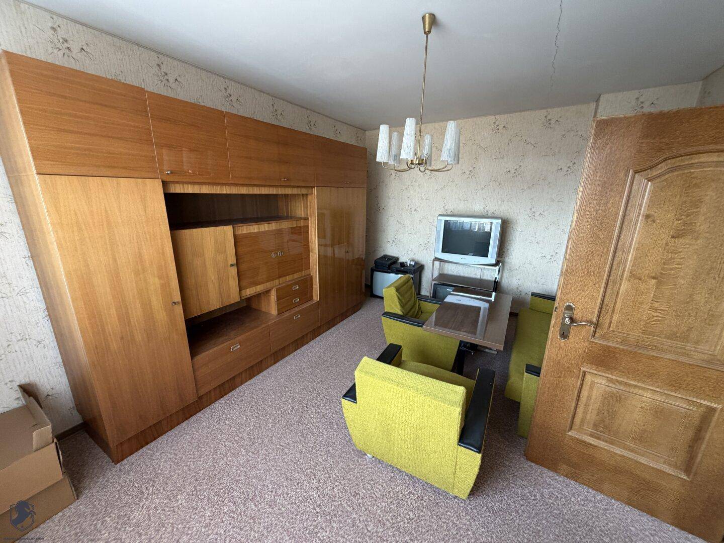 Wohnzimmer im Vintage-Stil mit großer Holzschrankwand und gelben Sesseln.