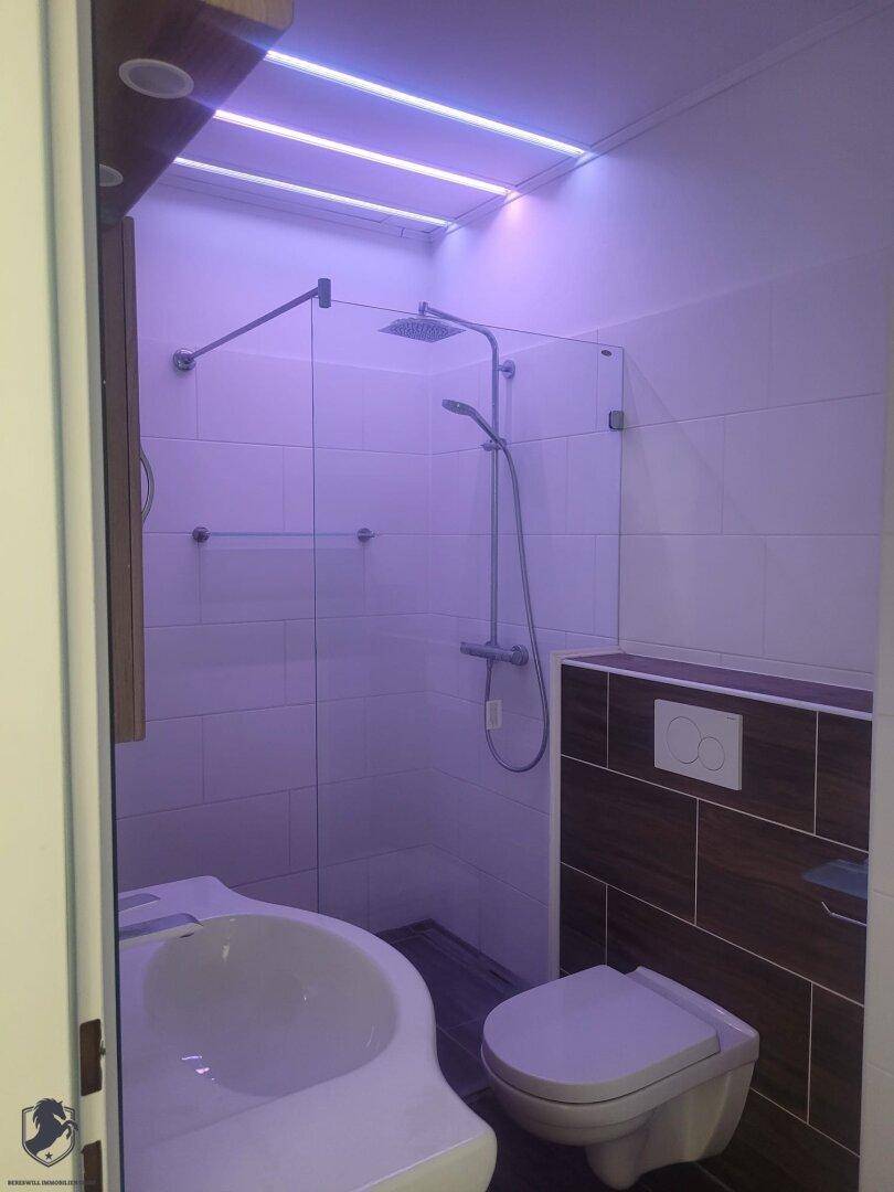 Modernes Badezimmer mit Glasduschkabine, wandhängendem WC, Bidet und LED-Beleuchtung.