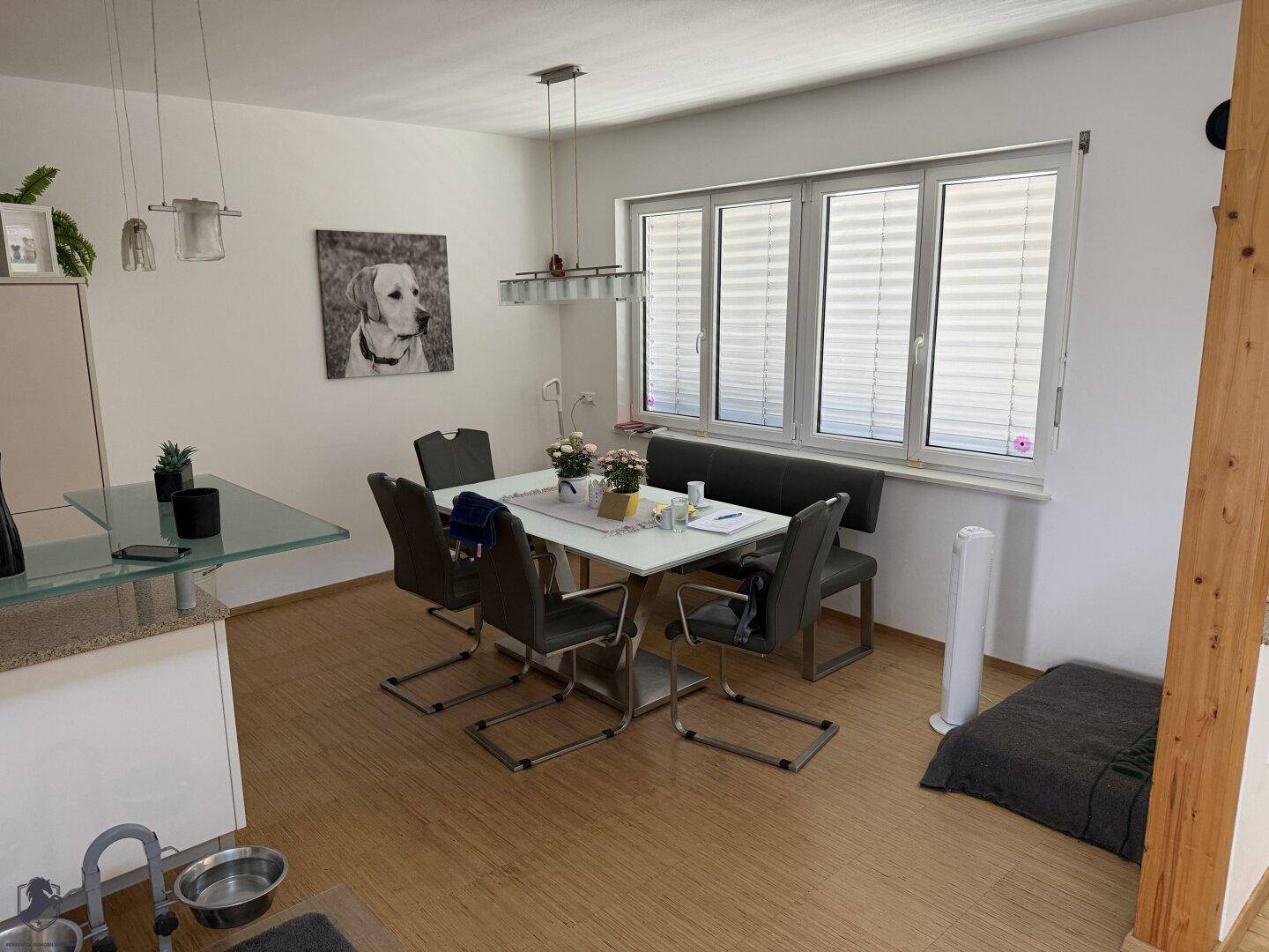Essbereich mit modernem Esstisch, Stühlen und einer Sitzbank vor einem großen Fenster.
