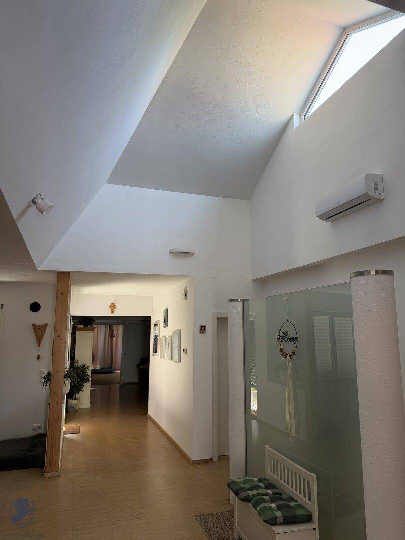 Heller Flur mit hohen Gewölbedecken, Oberlicht und einer Klimaanlage.