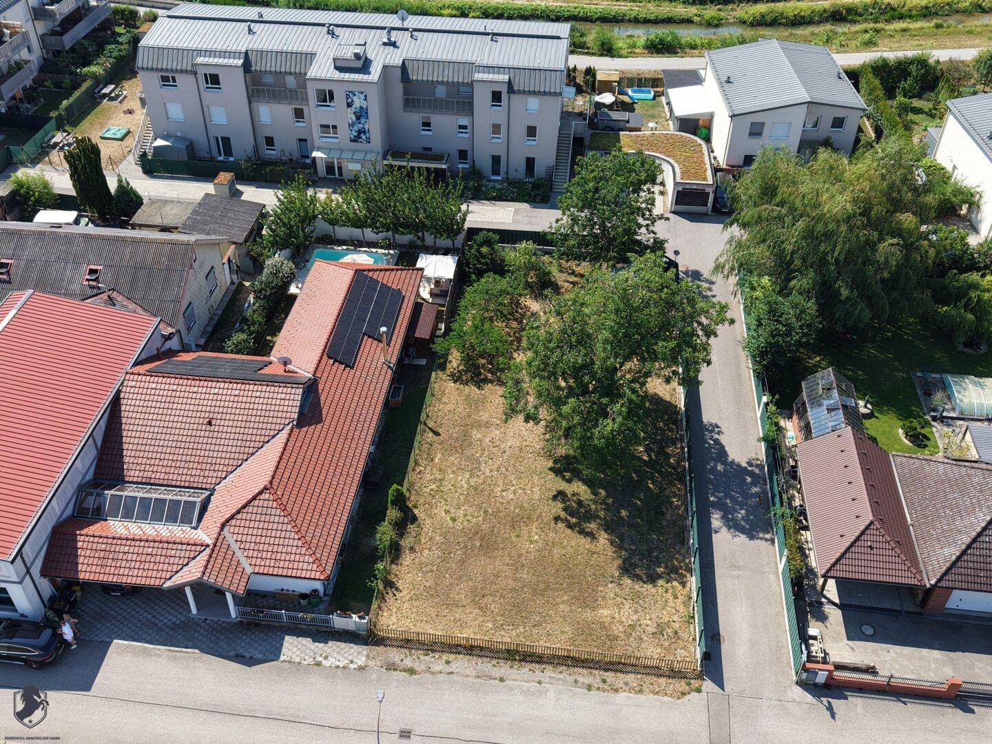 Luftaufnahme des Hauses mit angrenzendem unbebautem Grundstück und umliegender Bebauung.