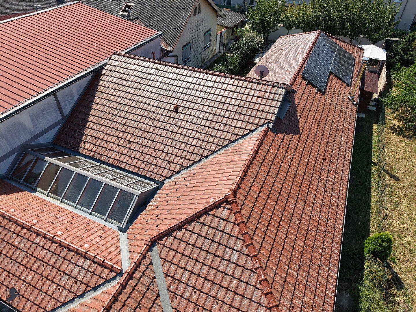 Nahaufnahme eines Ziegeldaches mit einem großen Dachfenster, das viel Licht spendet.