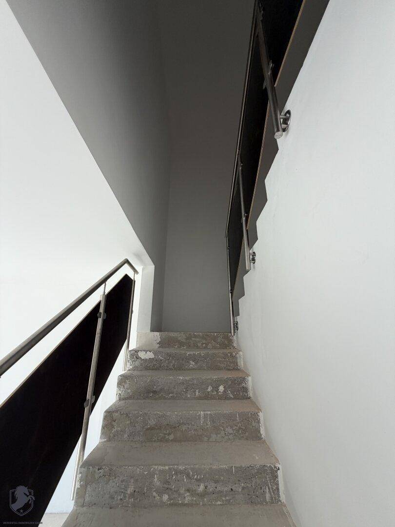 Unfertige Betontreppe in einem Neubau, die verschiedene Ebenen des Hauses verbindet.