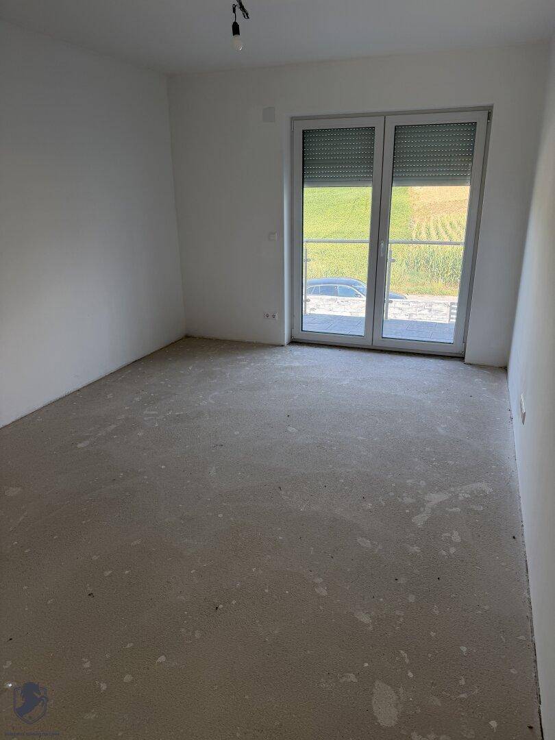 Geräumiges, unfertiges Zimmer mit Rohbetonboden und weitem Blick auf die Landschaft.