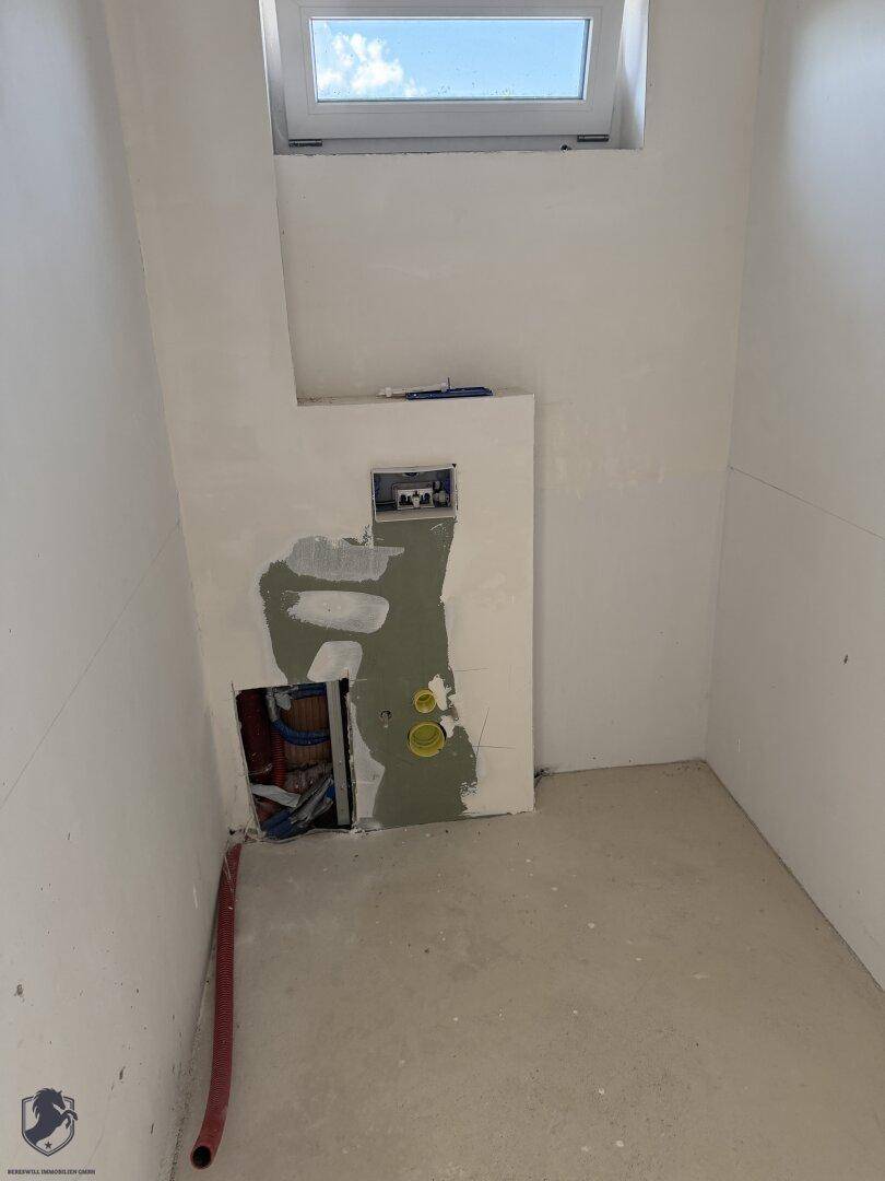 Unfertiges Badezimmer mit Dachfenster und vorbereiteten Anschlüssen für Sanitäranlagen.