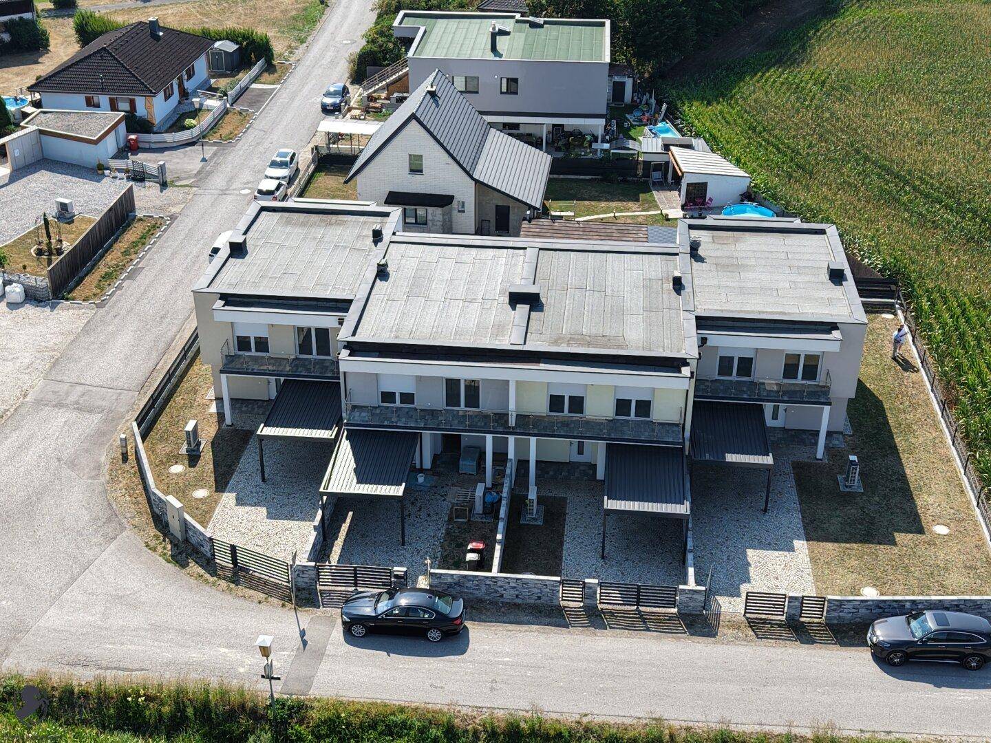 Vogelperspektive einer Reihe moderner Häuser mit Flachdächern und Carports.