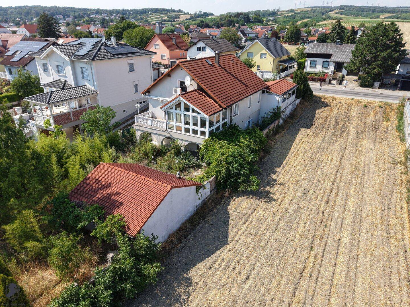 Weitläufige Luftaufnahme eines Hauses mit angrenzendem Feld und weiteren Wohnhäusern in der Ferne.