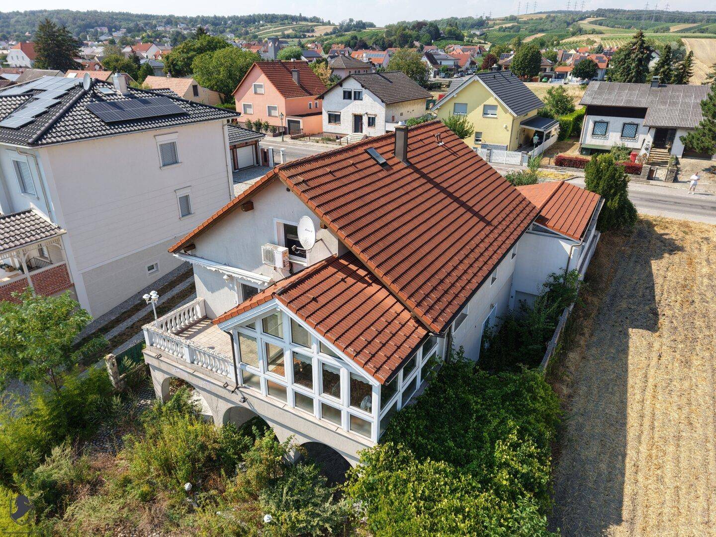 Luftaufnahme des Hauses mit rotem Ziegeldach, umgeben von Feldern und benachbarten Wohnhäusern.