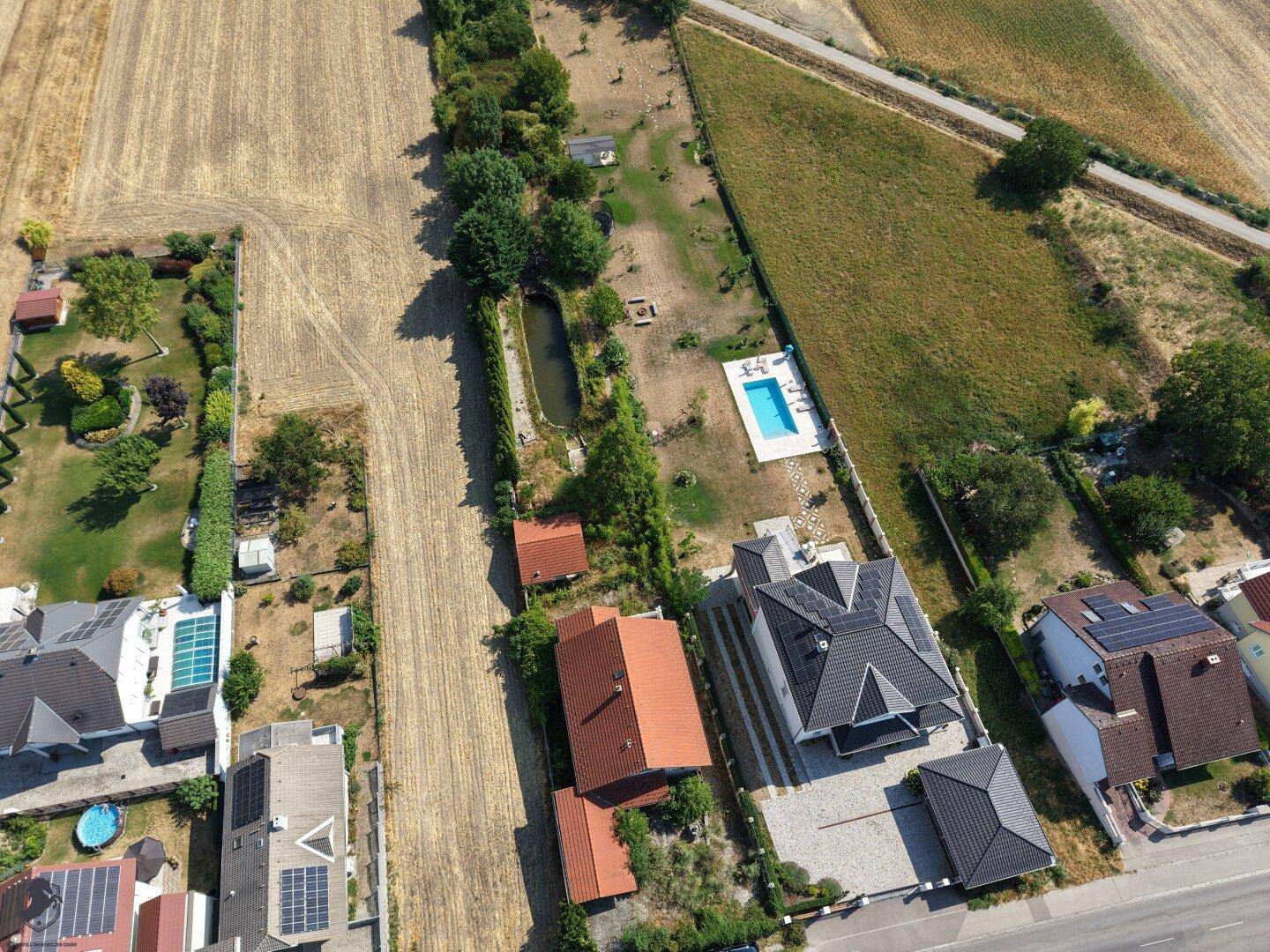 Weitläufige Luftaufnahme des Anwesens mit Teich, Pool in der Nachbarschaft und umliegenden Feldern.