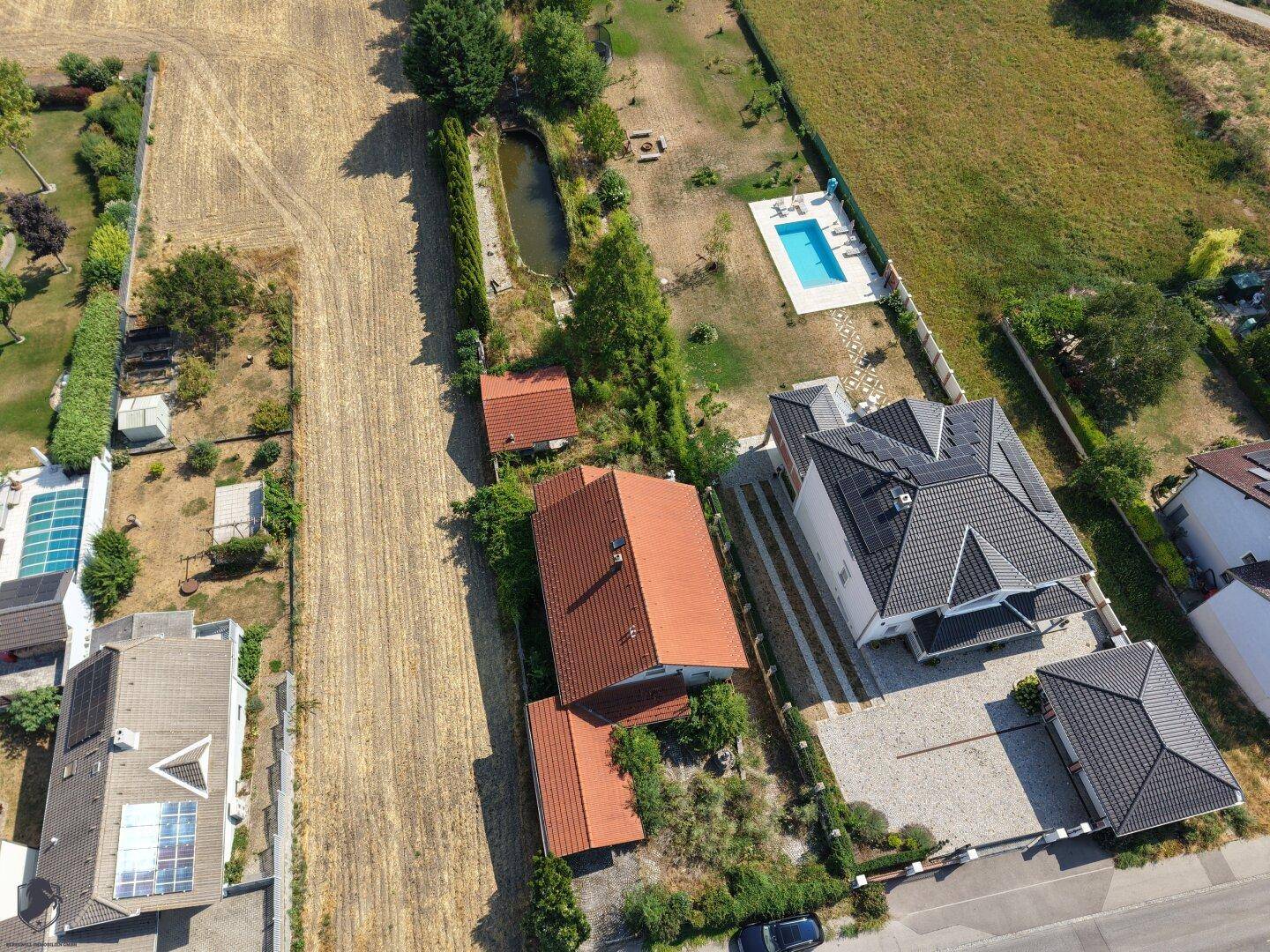 Übersichtliche Luftaufnahme des Grundstücks mit Teich, Pool und der ländlichen Umgebung.