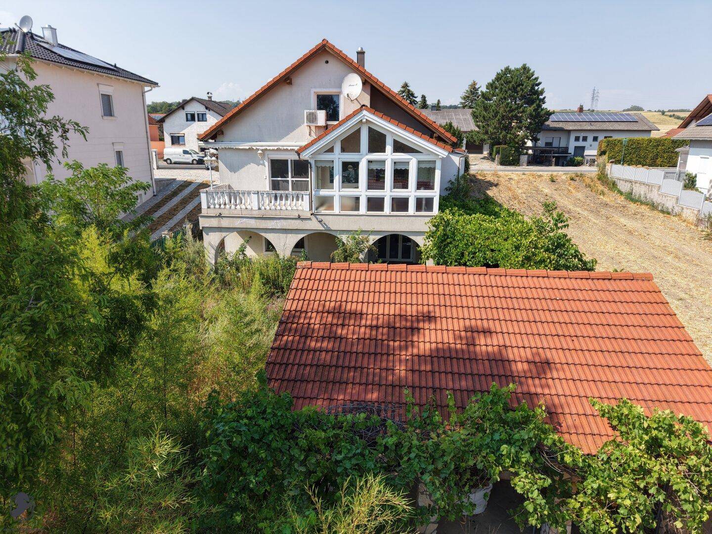 Weitläufige Luftaufnahme eines Hauses mit angrenzendem Feld und weiteren Wohnhäusern in der Ferne.