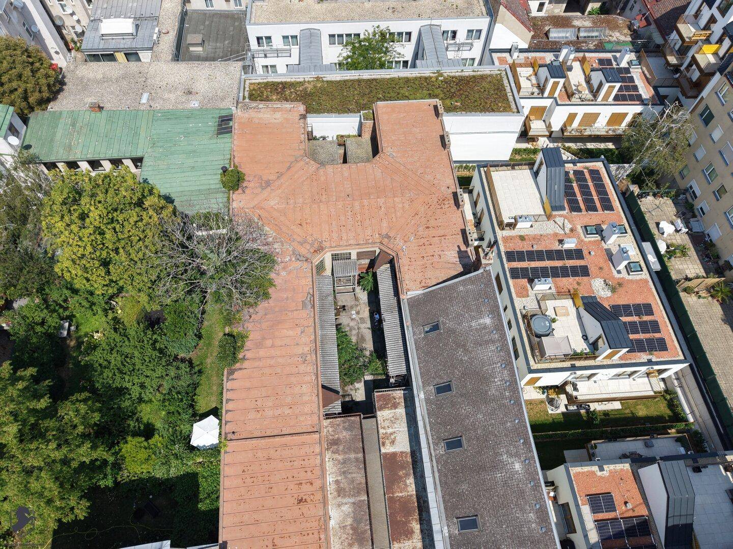 Luftaufnahme von Dächern und Innenhöfen, mit Solaranlagen auf einem benachbarten Gebäude.