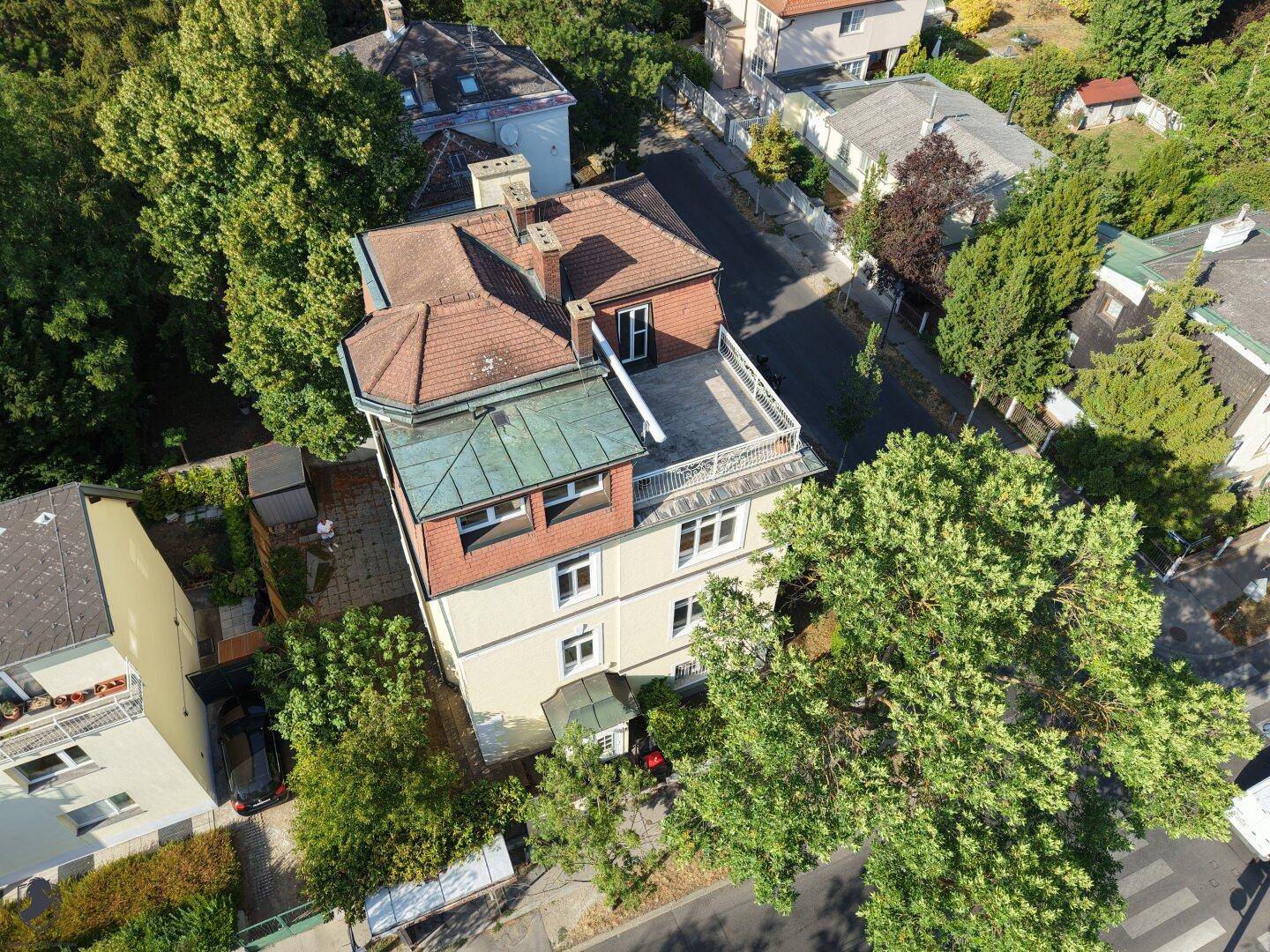 Luftaufnahme des Anwesens mit Mansarddach, umliegenden Gebäuden und üppiger Baumlandschaft.