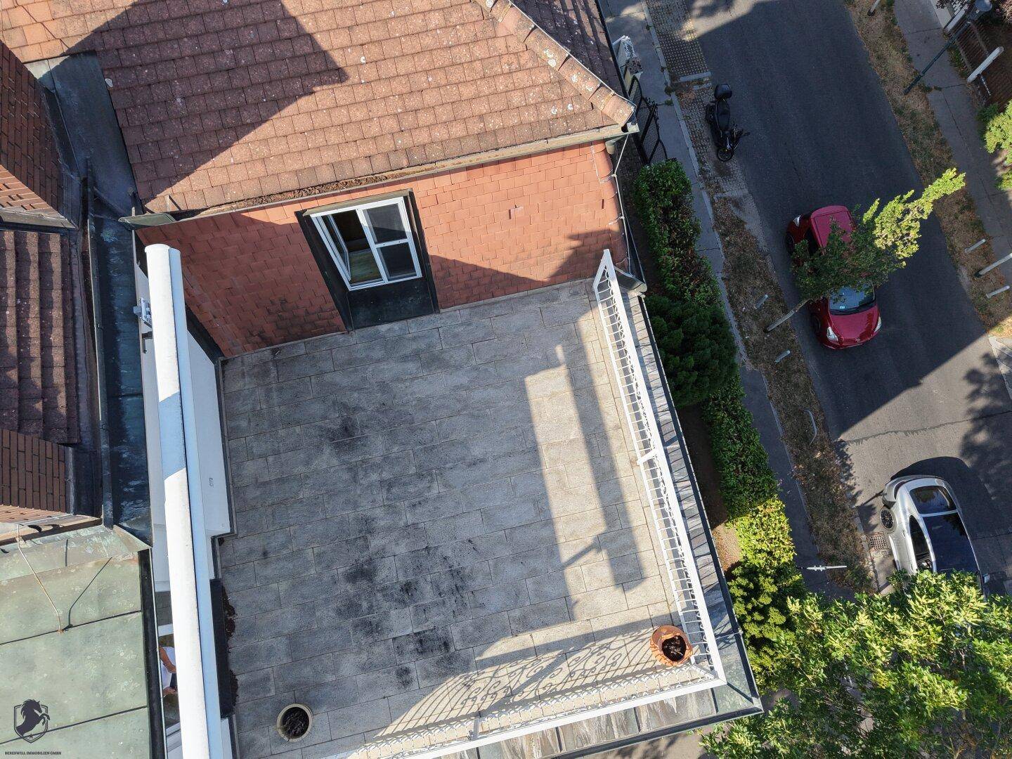 Großzügige Dachterrasse mit Steinplattenboden und weißem Geländer, ideal für entspannte Stunden im Freien.