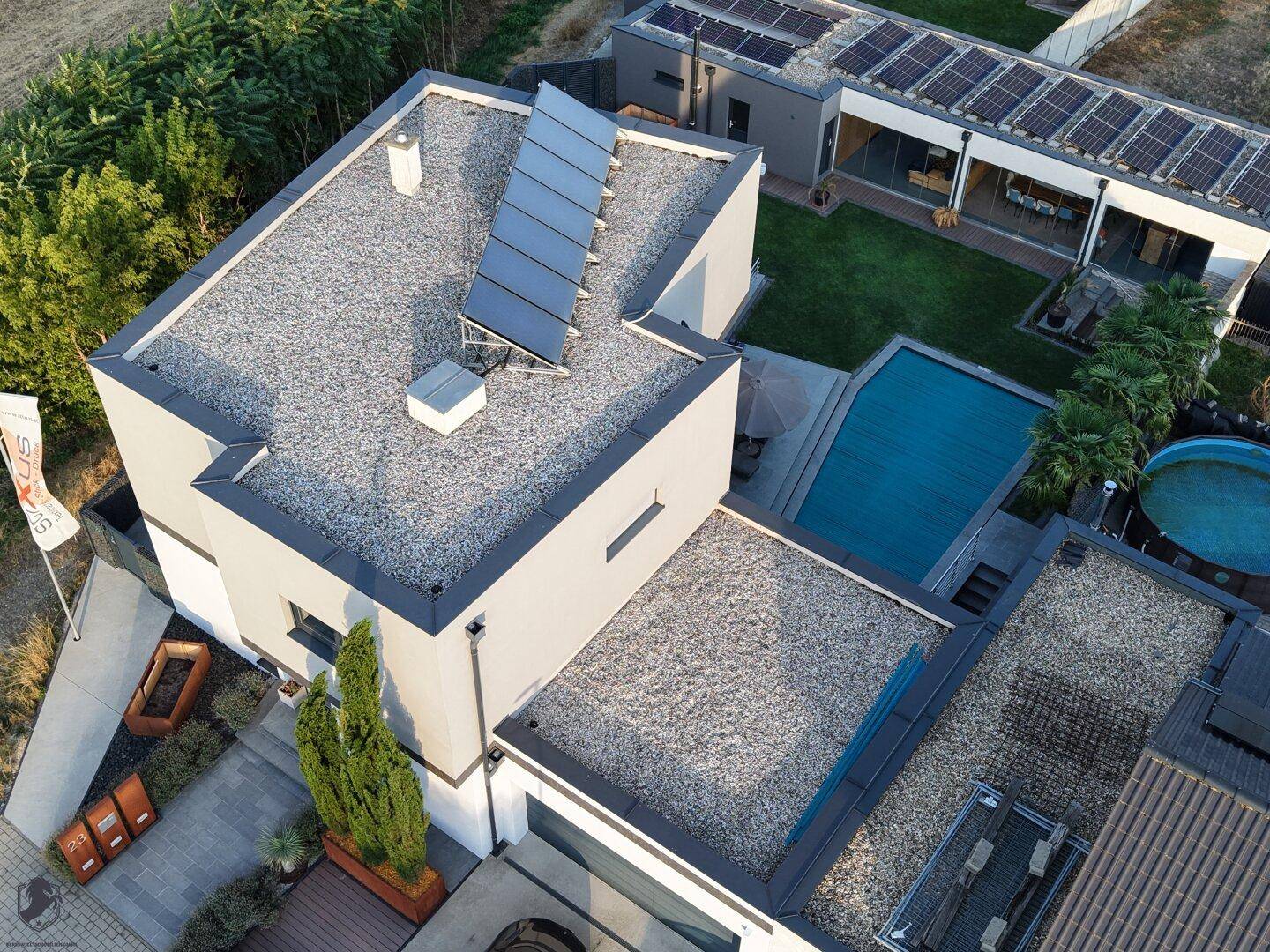 Luftaufnahme des modernen Hauses mit Flachdach, Solaranlage und privatem Poolbereich.