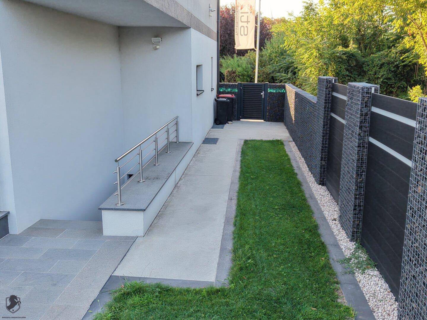 Seitlicher Zugang zum Grundstück mit barrierefreier Rampe und stabilem Handlauf.