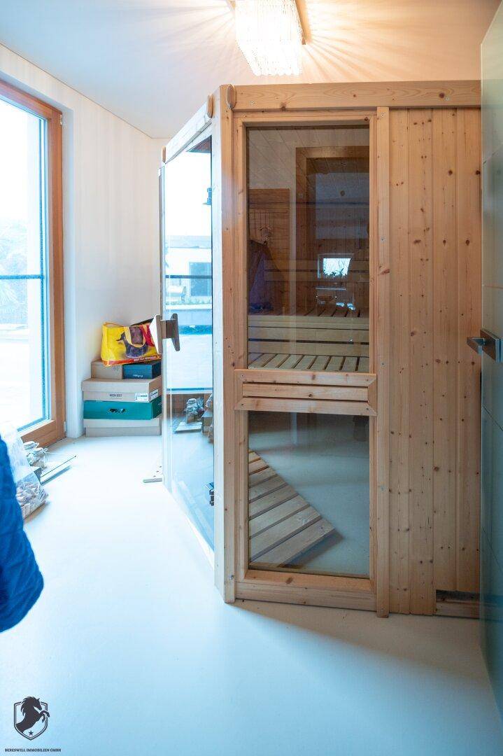 Moderne Sauna mit Holzausstattung und großem Fenster für natürliche Belichtung.