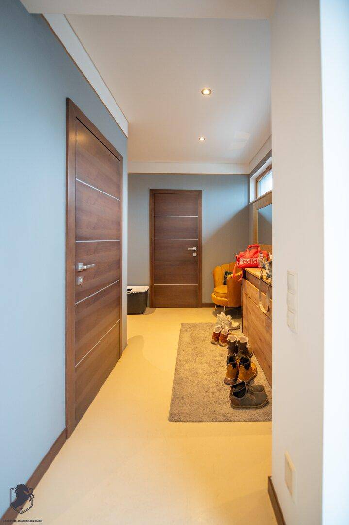 Heller Flur mit modernen Holztüren und praktischem Schuhregal.