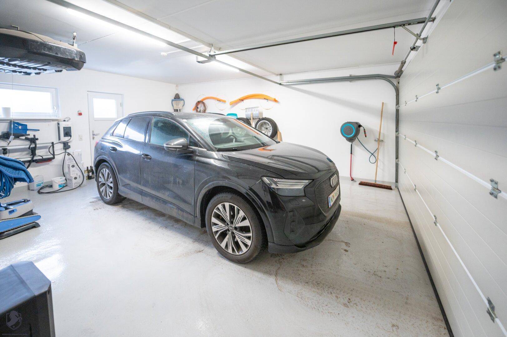 Geräumige Garage mit Elektrofahrzeug und installierter Ladestation.