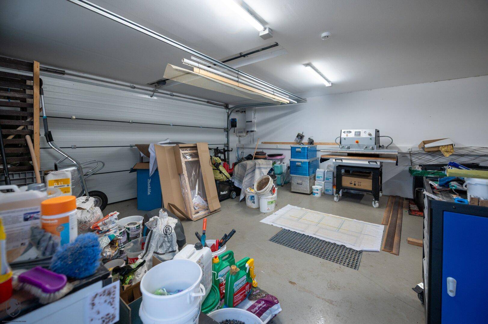 Geräumige Garage oder Werkstatt mit Betonboden und viel Stauraum für Werkzeuge und Materialien.