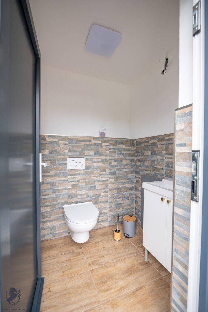 Helles Gäste-WC mit zeitgemäßer Ausstattung, wandhängender Toilette und stilvollen Fliesen im unteren Bereich.