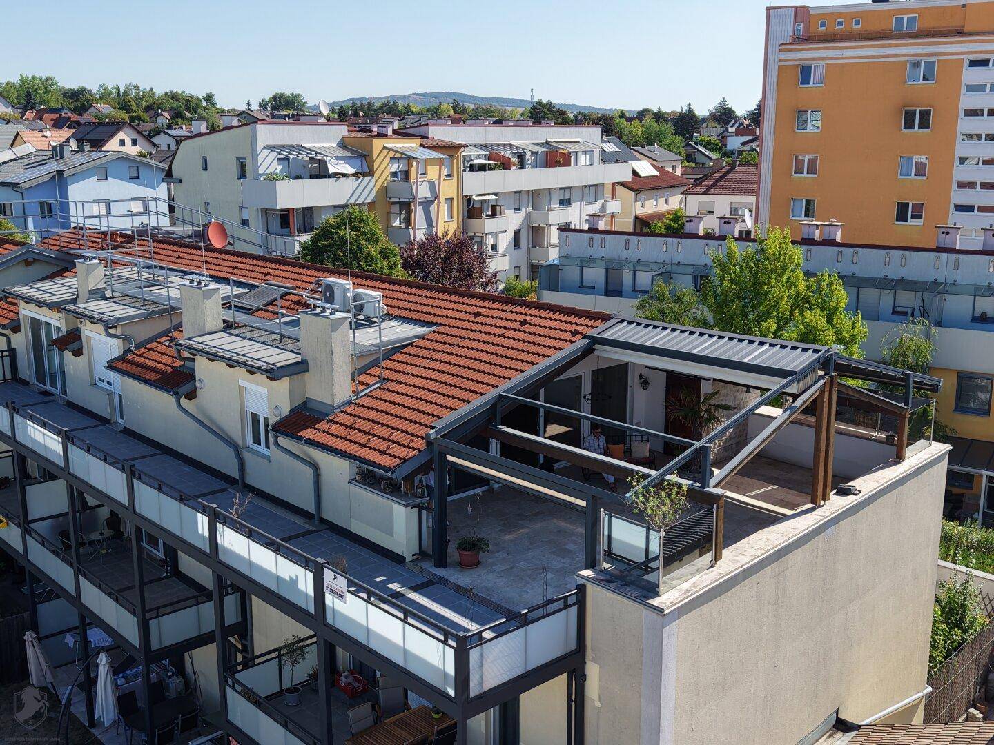 Dachaufsicht des Wohngebäudes mit Terrassenbereichen und Blick auf die umliegende Nachbarschaft.