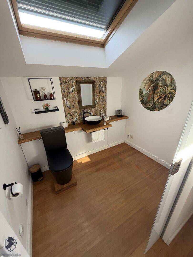 Modernes Gäste-WC mit Holzboden, Dachfenster und stilvoller Tapete.