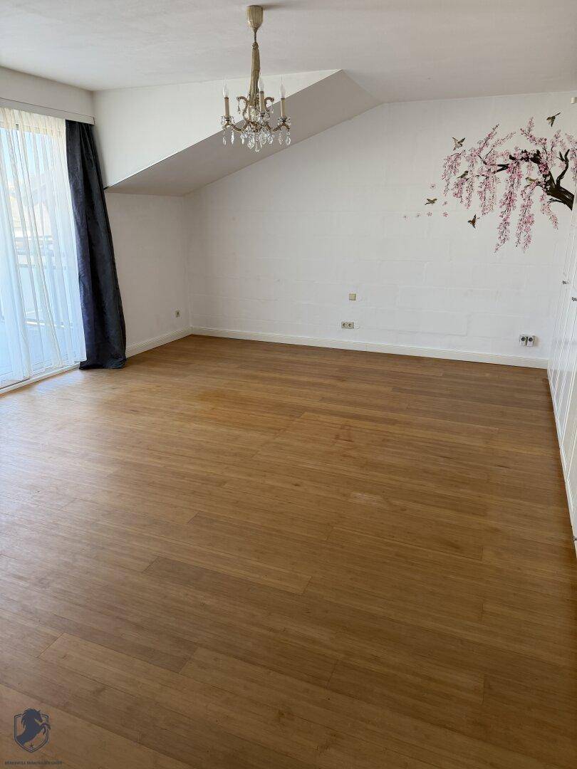 Helles Schlafzimmer mit Holzboden, Dachschräge und großen Fenstern, die viel Licht hereinlassen.