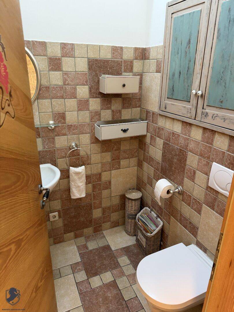 Kleines Gäste-WC mit Fliesenboden, Wandfliesen und einem kleinen Waschbecken.