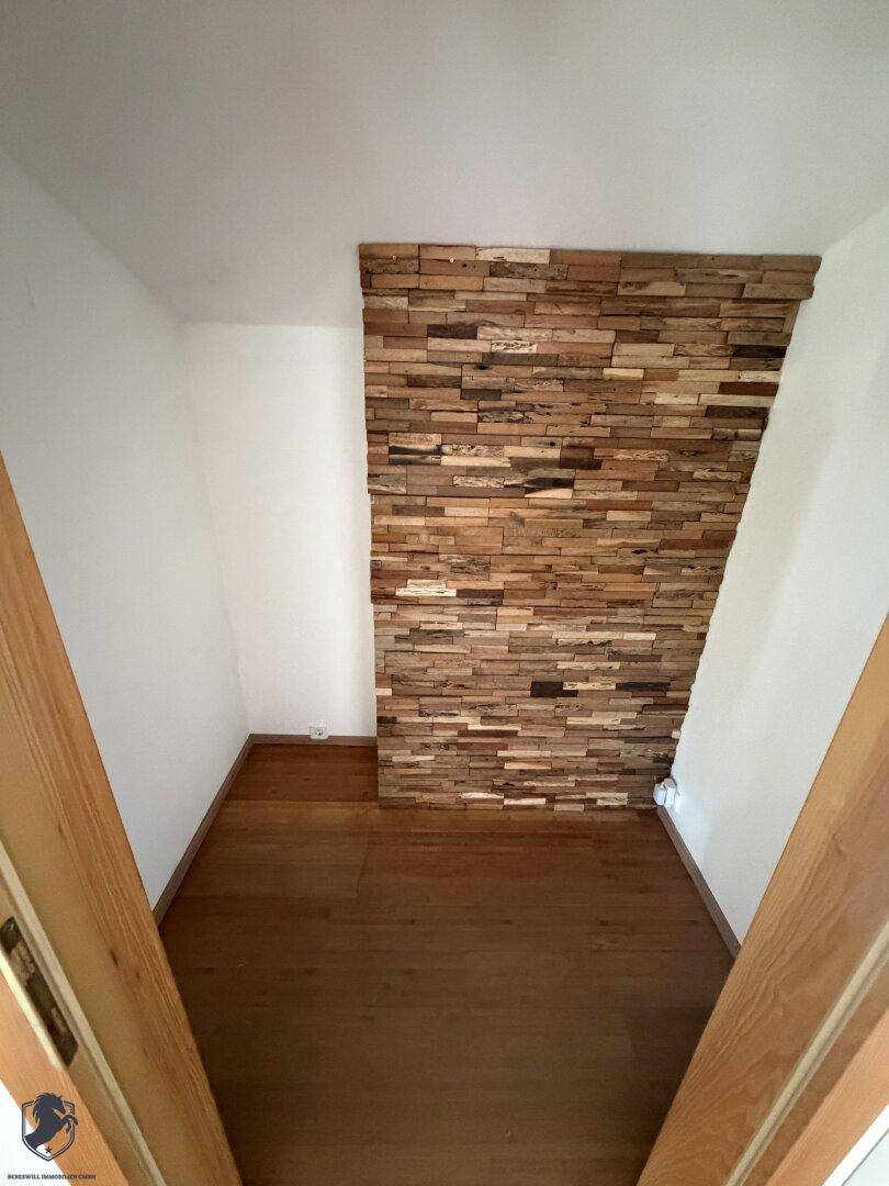 Kleiner Raum mit dekorativer Holzwandverkleidung und Holzboden.
