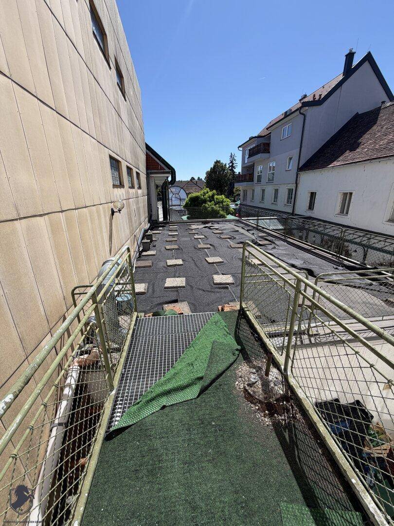 Große, ungenutzte Dachterrasse oder Außenfläche zwischen Gebäuden mit Metallgeländern.