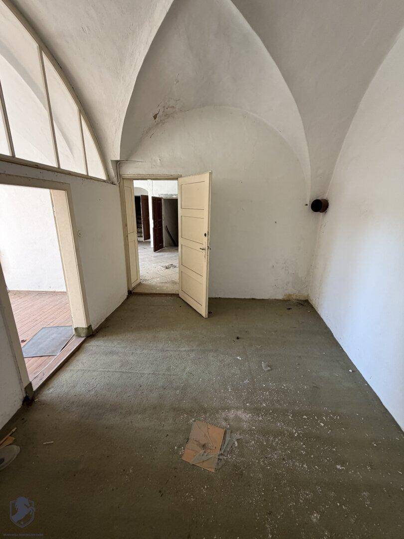 Leerer Raum mit beeindruckender Gewölbedecke und mehreren Türen, die zu anderen Bereichen führen.