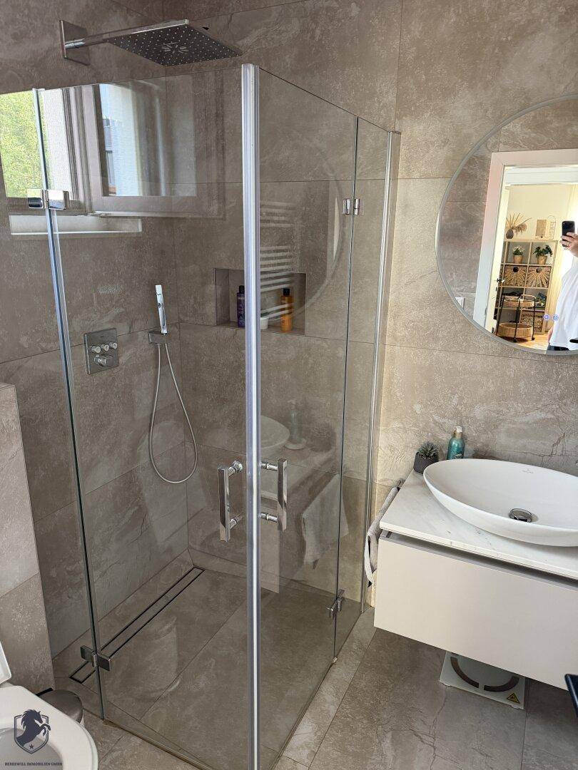 Modernes Badezimmer mit begehbarer Glasdusche, stilvollem Waschbecken und großen Fliesen.