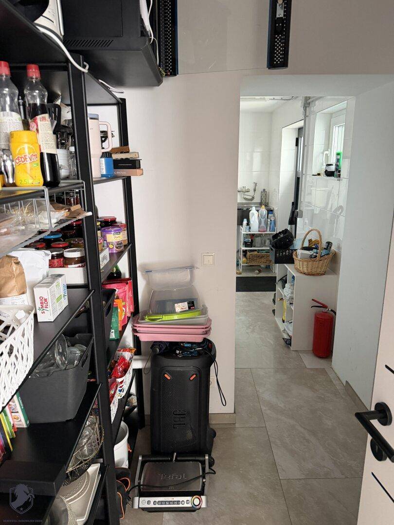 Praktische Speisekammer mit Regalen für Vorräte und Zugang zu einem weiteren Nebenraum.