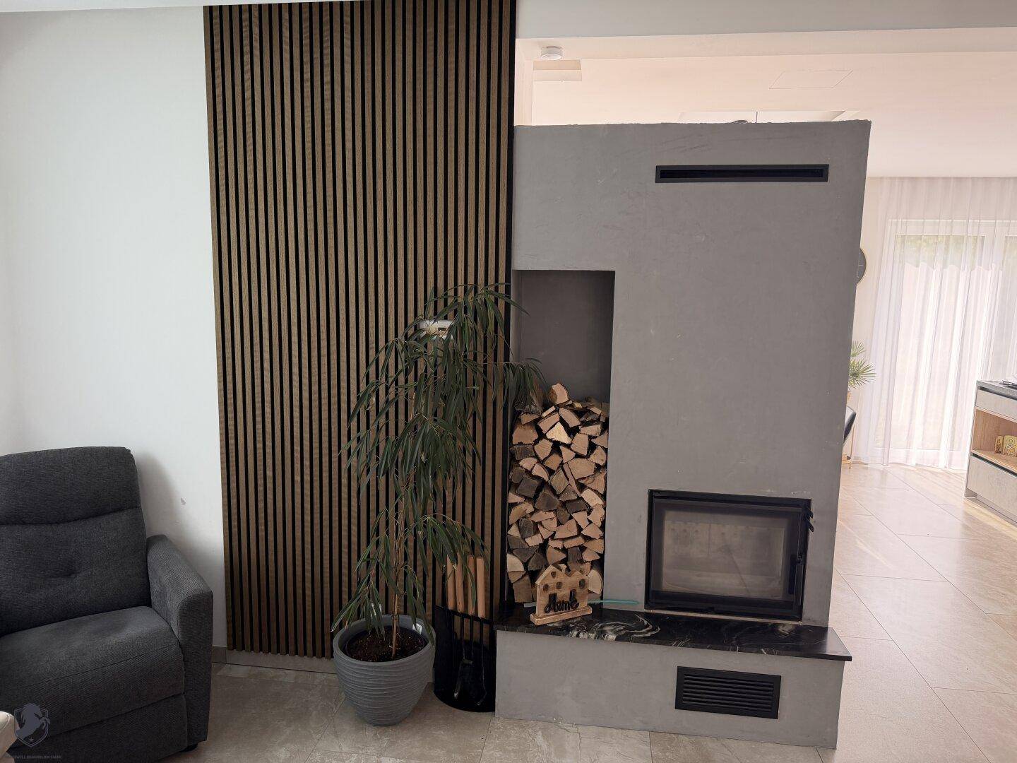 Wohnzimmer mit modernem Kamin, integriertem Holzregal und dekorativer Holzlamellenwand.