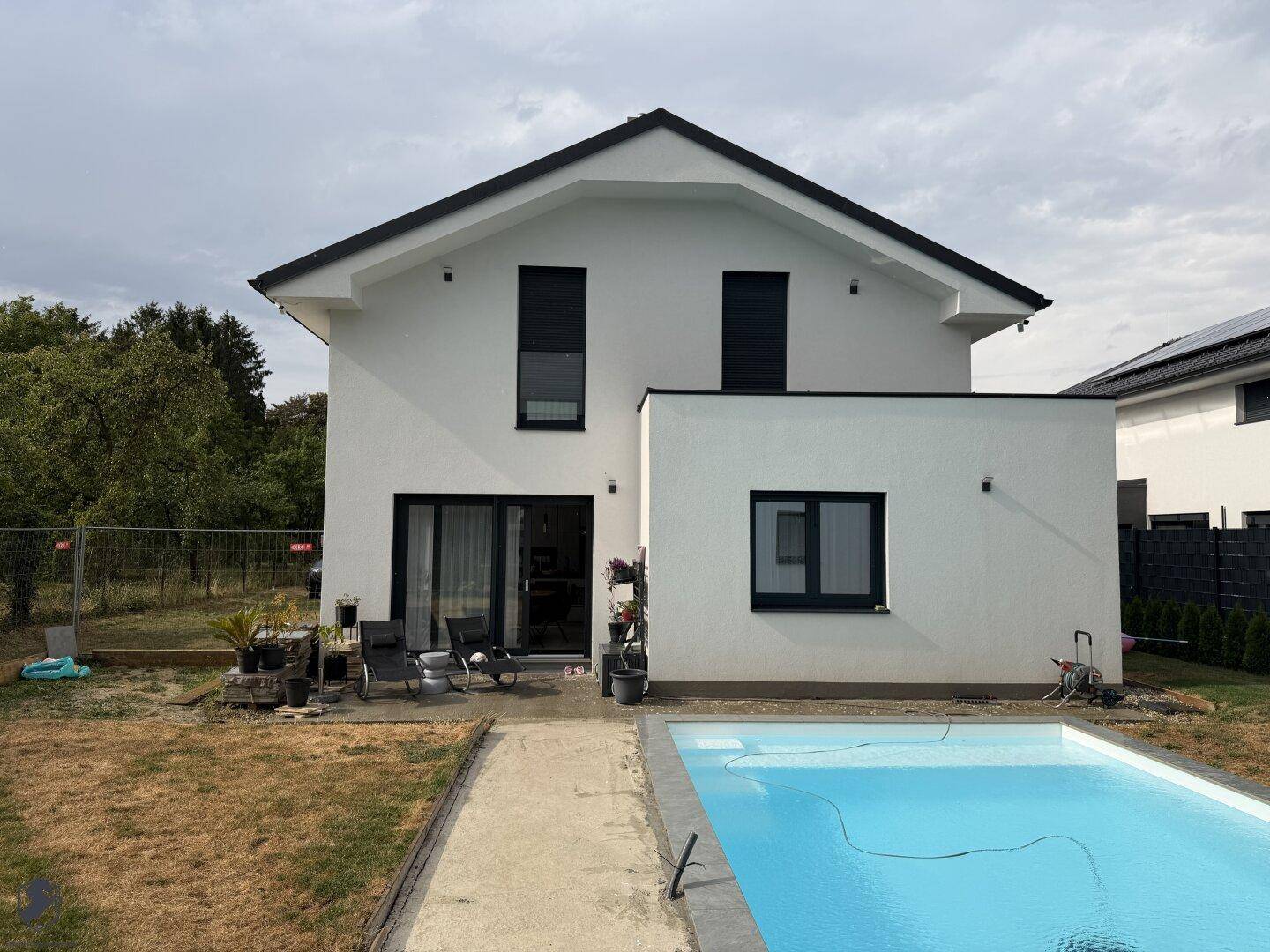 Rückseite des Hauses mit direktem Zugang zum Poolbereich und einer kleinen Terrasse.