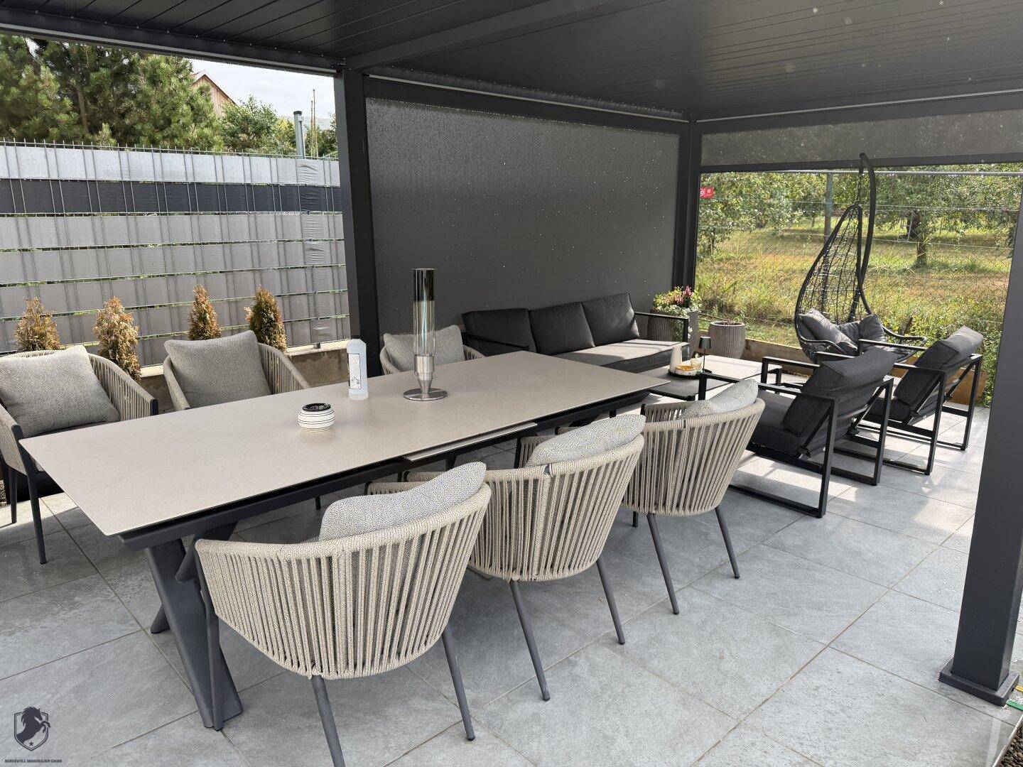 Gemütlicher Loungebereich auf der überdachten Terrasse mit bequemen Sitzgelegenheiten und Blick ins Grüne.