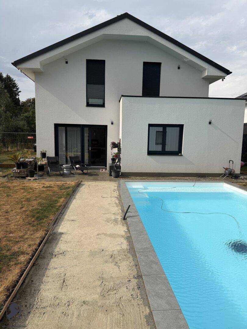 Rückansicht des Hauses mit Swimmingpool und einer noch zu gestaltenden Gartenfläche.
