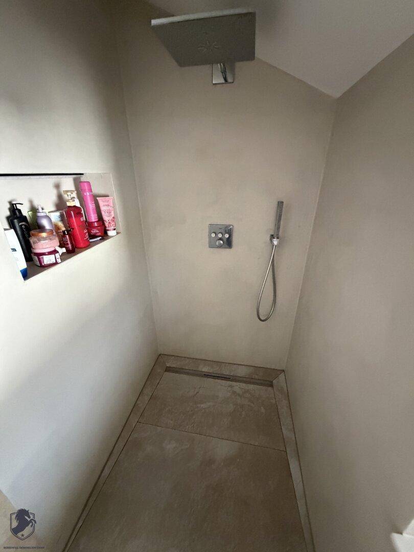Moderne Duschkabine mit Regendusche und integrierten Ablagen in minimalistischem Design.