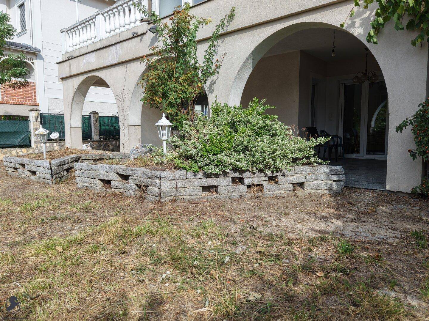 Geräumige Loggia mit Steinmauern und Blick auf den Gartenbereich des Anwesens.