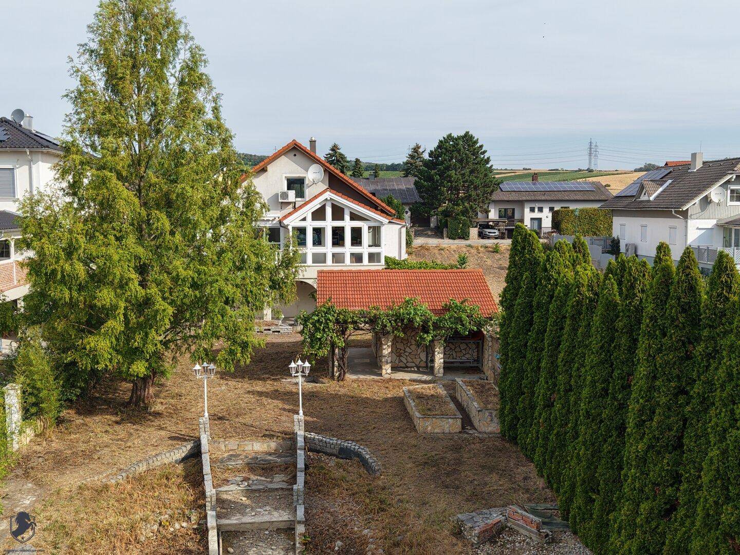 Weitläufige Ansicht des Anwesens mit Garten, Teich und umliegender Landschaft.