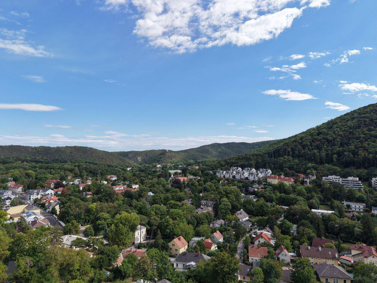 Panoramablick über die grüne Hügellandschaft mit verstreuten Häusern und weitem Himmel.