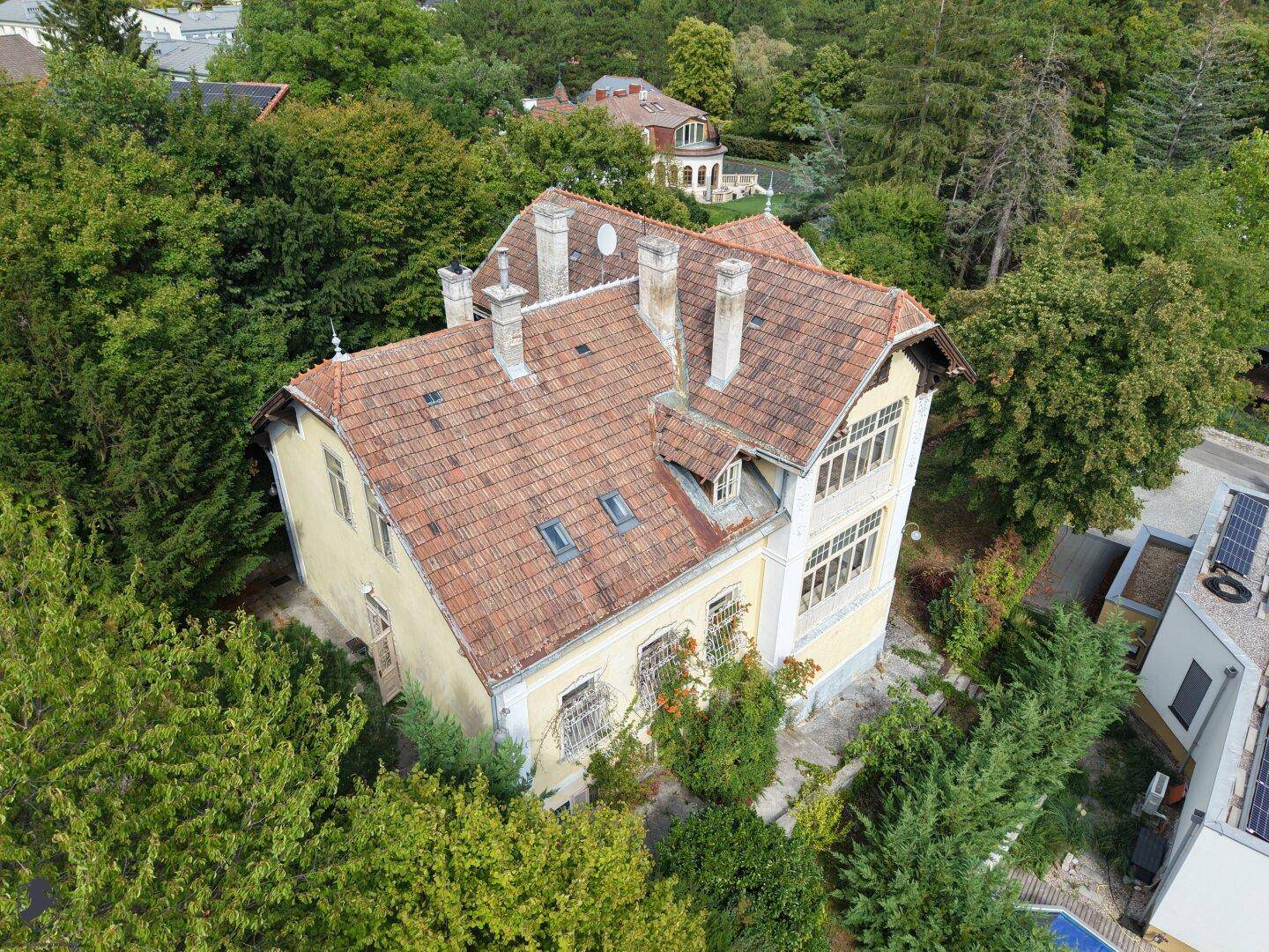 Luftaufnahme der historischen Villa mit Terrakottadach und umgebendem Baumbestand.