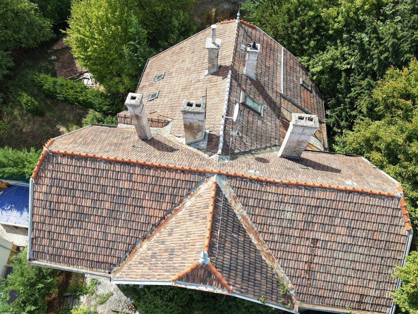 Detailansicht des Terrakottadachs der historischen Villa mit mehreren Schornsteinen.