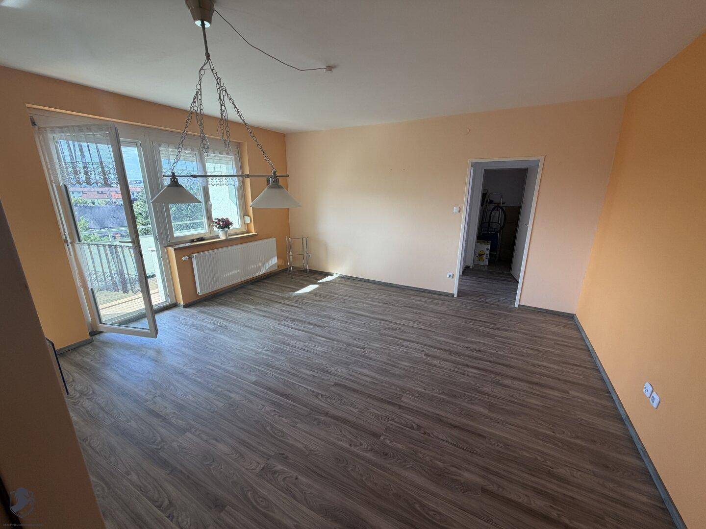 Geräumiges Wohnzimmer mit Laminatboden und hellen Wänden, bereit zur individuellen Gestaltung.