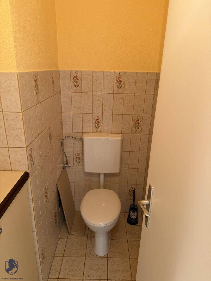 Separates WC mit floral gemusterten Wandfliesen und Steh-WC.