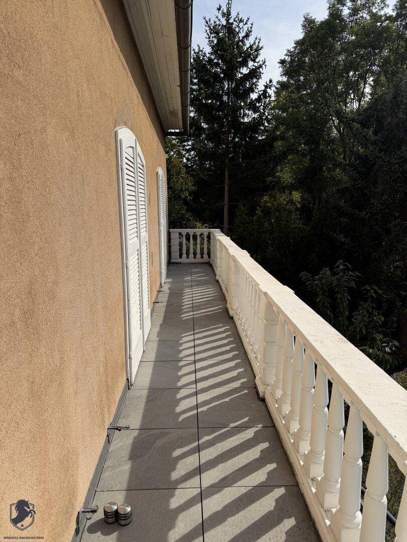 Langer Balkon mit weißem Geländer und Fensterläden, ideal für entspannte Stunden im Freien.