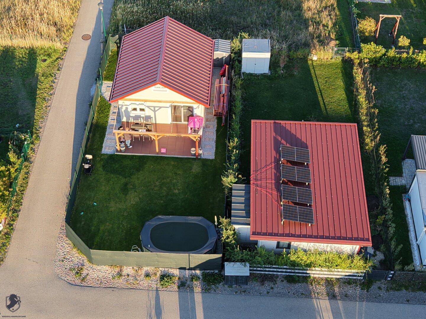 Detaillierte Luftaufnahme des Hauses mit Terrasse, Garten und Nebengebäude mit Solarmodulen.
