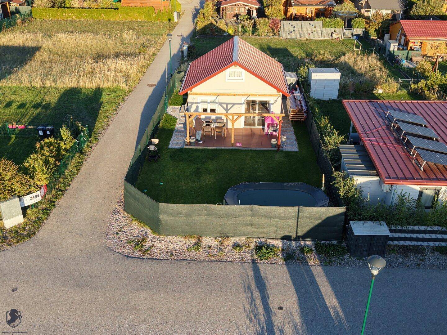 Übersicht des Hauses mit Garten, möblierter Terrasse und angrenzendem Gebäude in sonniger Lage.